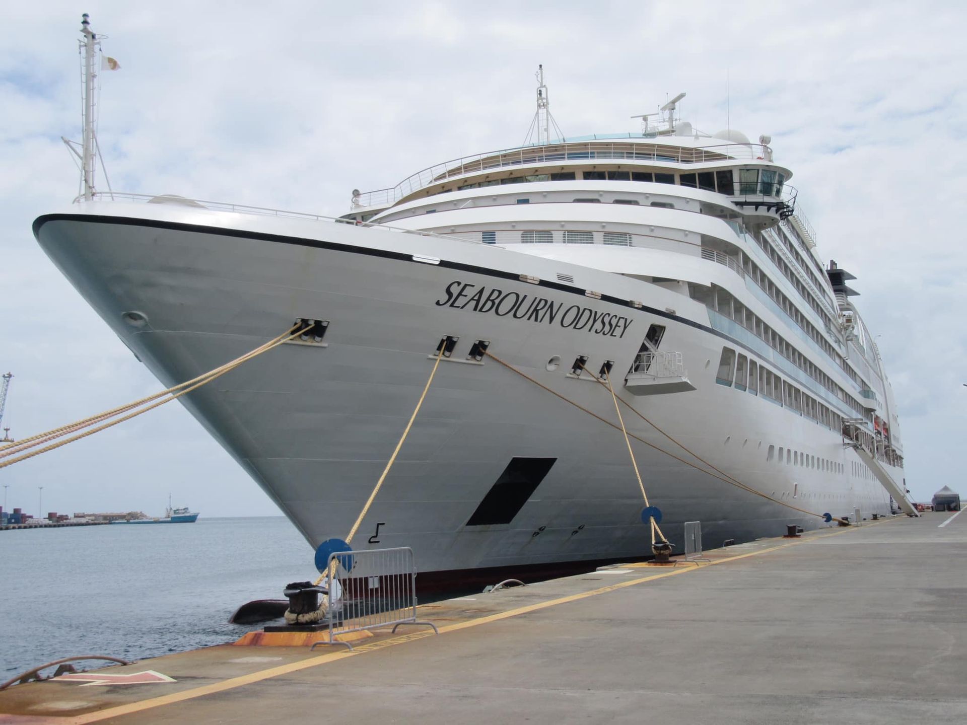 Seabourn Odyssey cruise ship docked at a pier, under a cloudy sky.