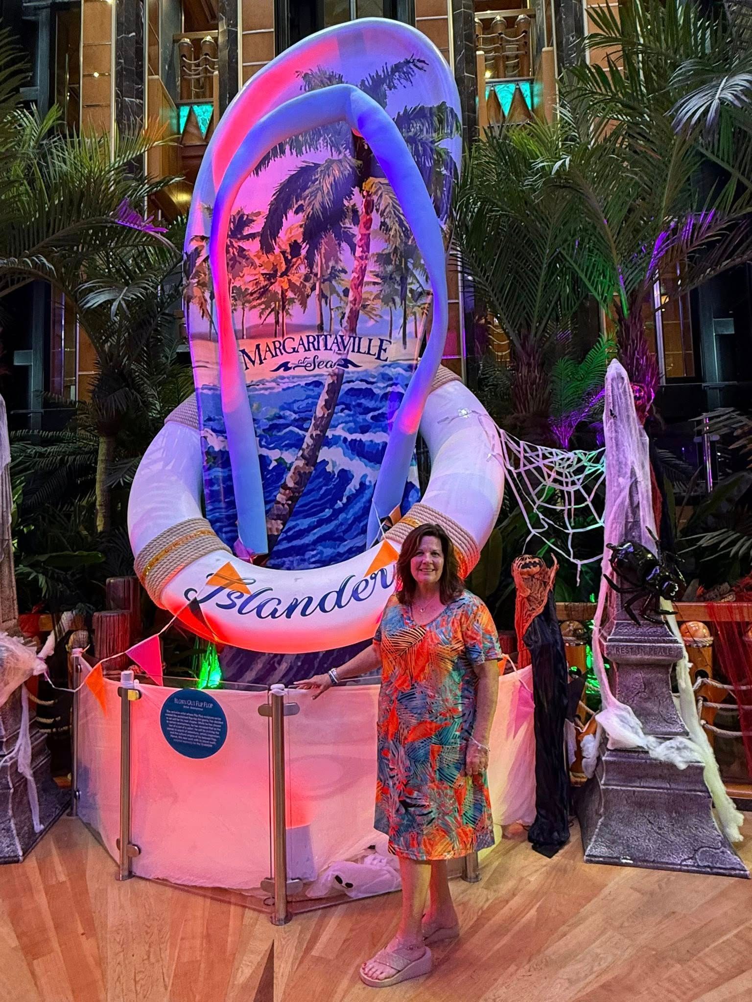 Person pointing at a laptop screen on a desk with a globe, camera, and small plane model.