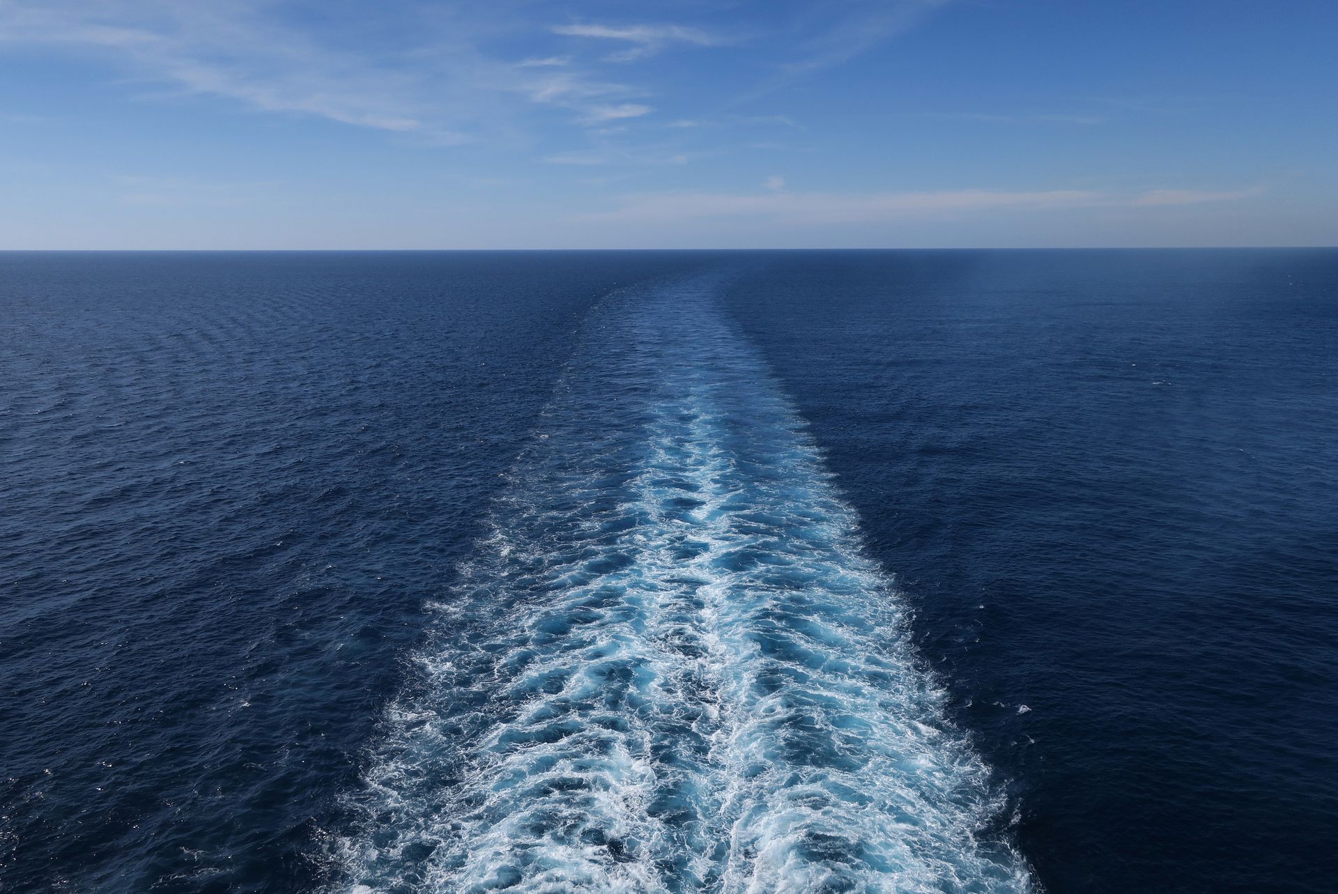 People on a sailboat enjoying the sunny ocean, arms raised.