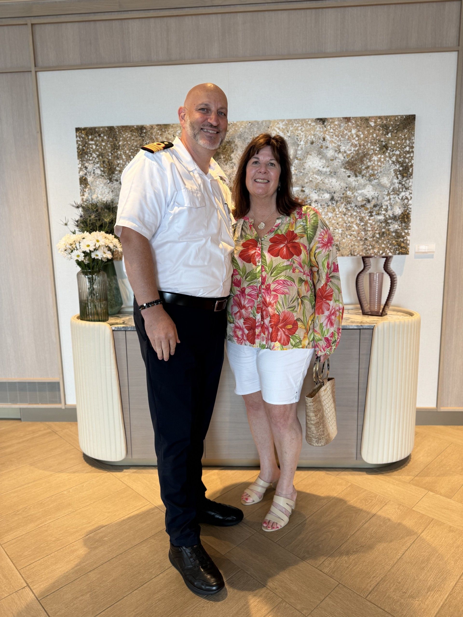 Couple taking a selfie on a boat with city skyline in the background. Blue water and sky.