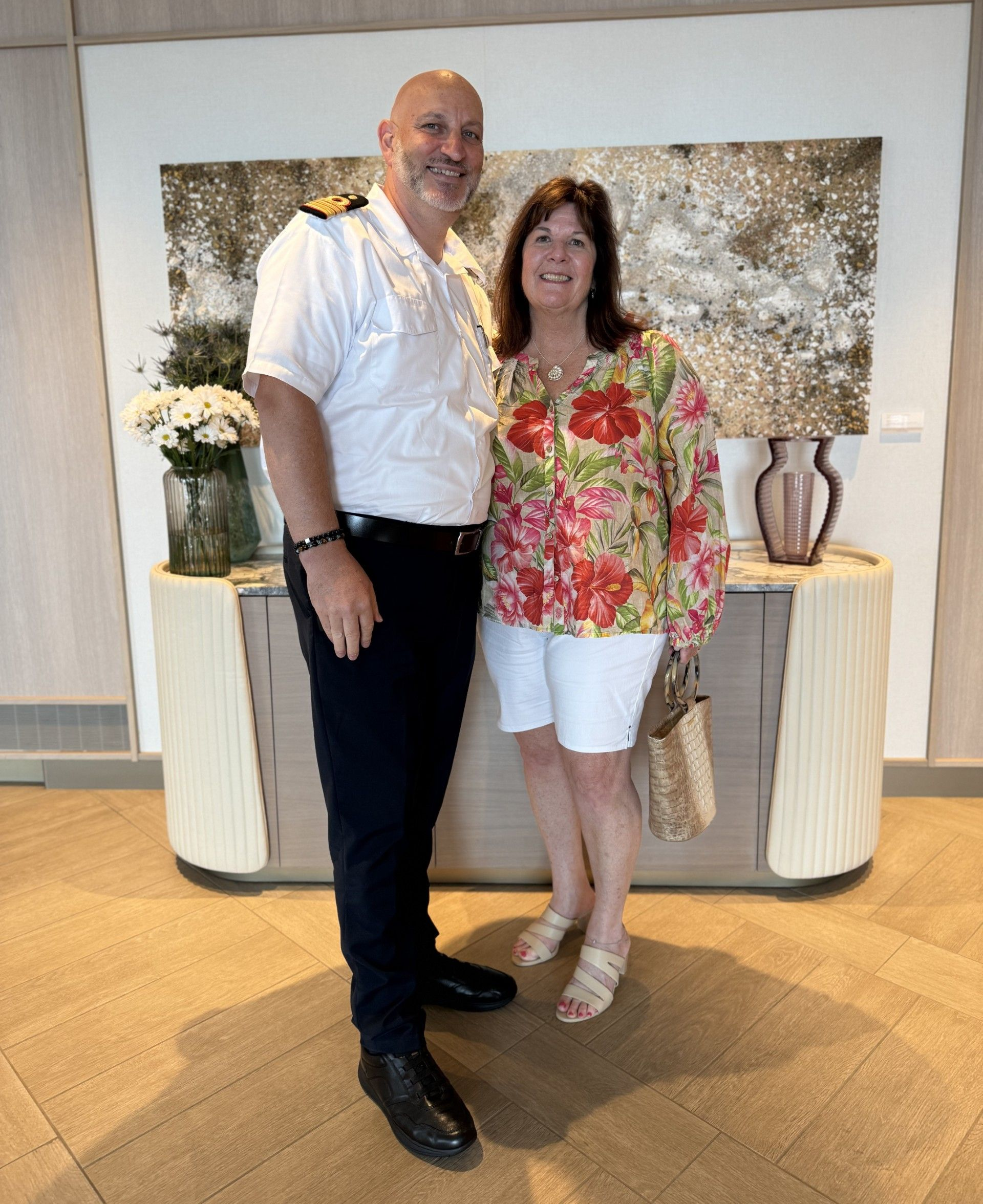 Couple taking a selfie on a boat with city skyline in the background. Blue water and sky.
