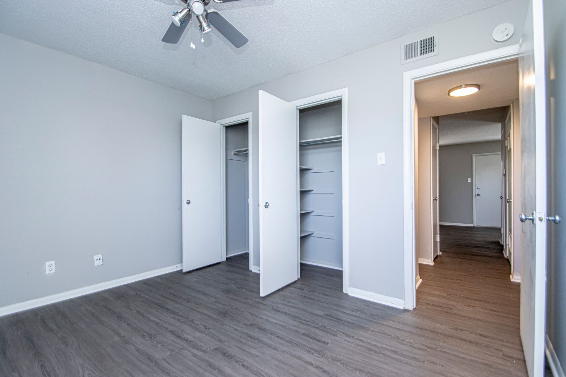 Empty bedroom with gray walls, closet, and open doorway to hallway.