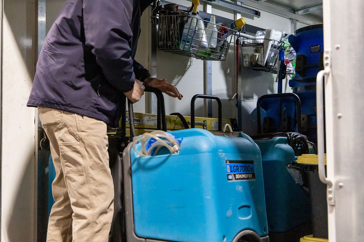 A man is standing next to a blue container in a room.
