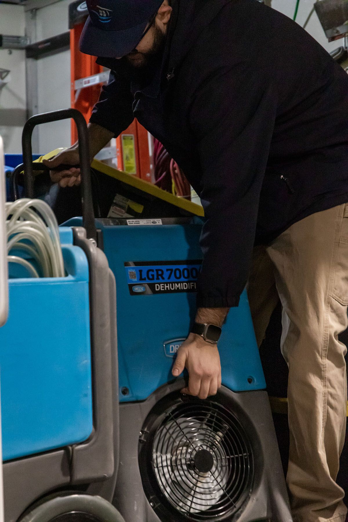 A man is working on a fan in a garage.