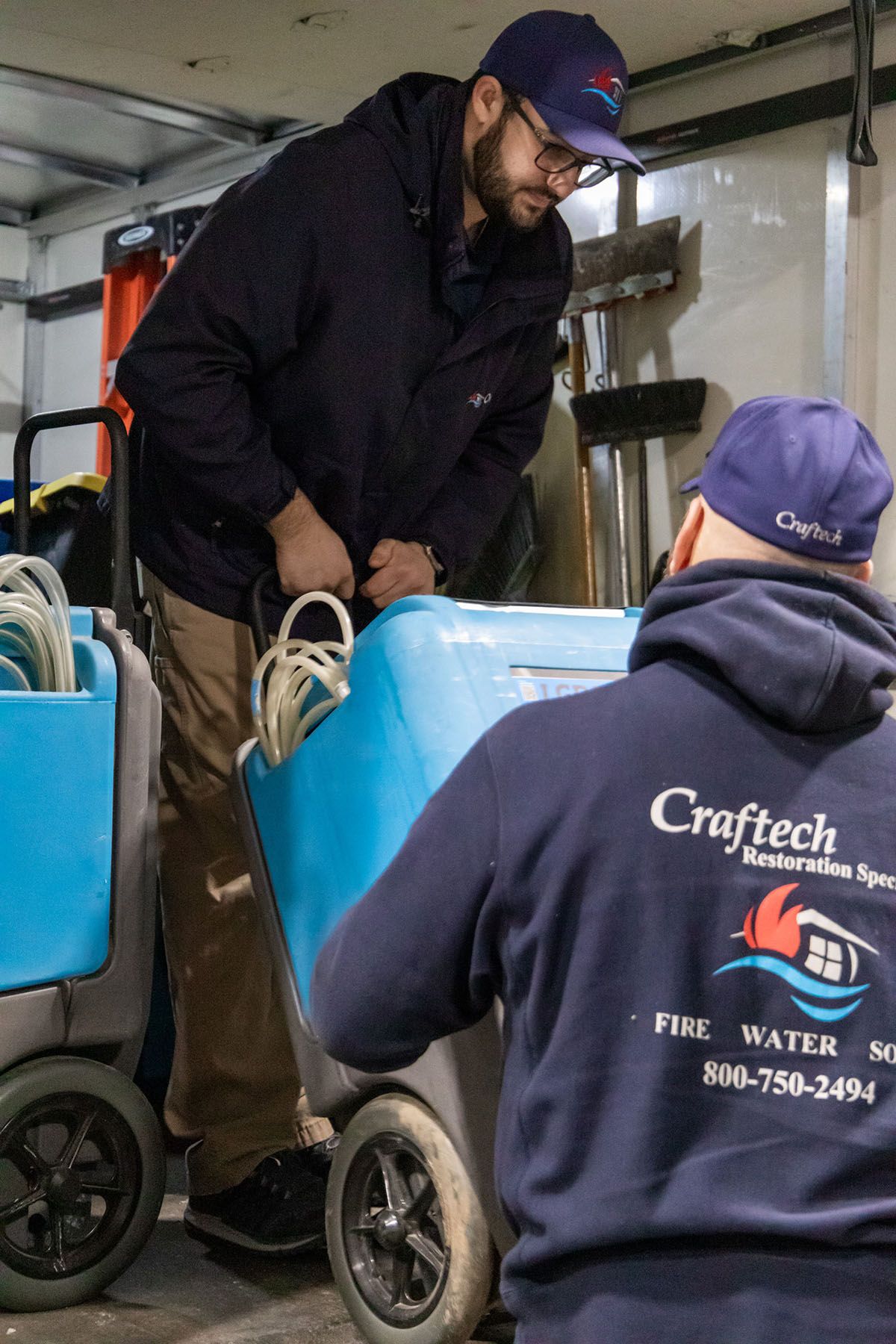 A man wearing a craftech sweatshirt is pushing a cart