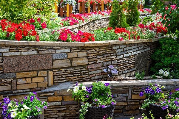 Retaining walls in St. Charles, MO, with flowerbeds in residential house backyard, showing Lemay Concrete Block’s services.