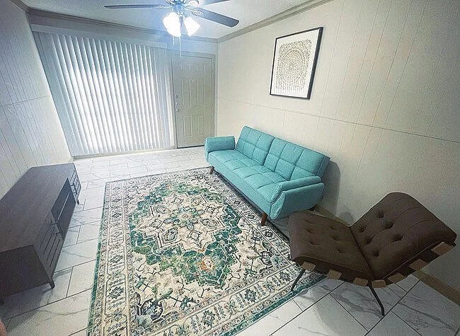 Living room with teal sofa, patterned rug, brown chair, and artwork on wall.