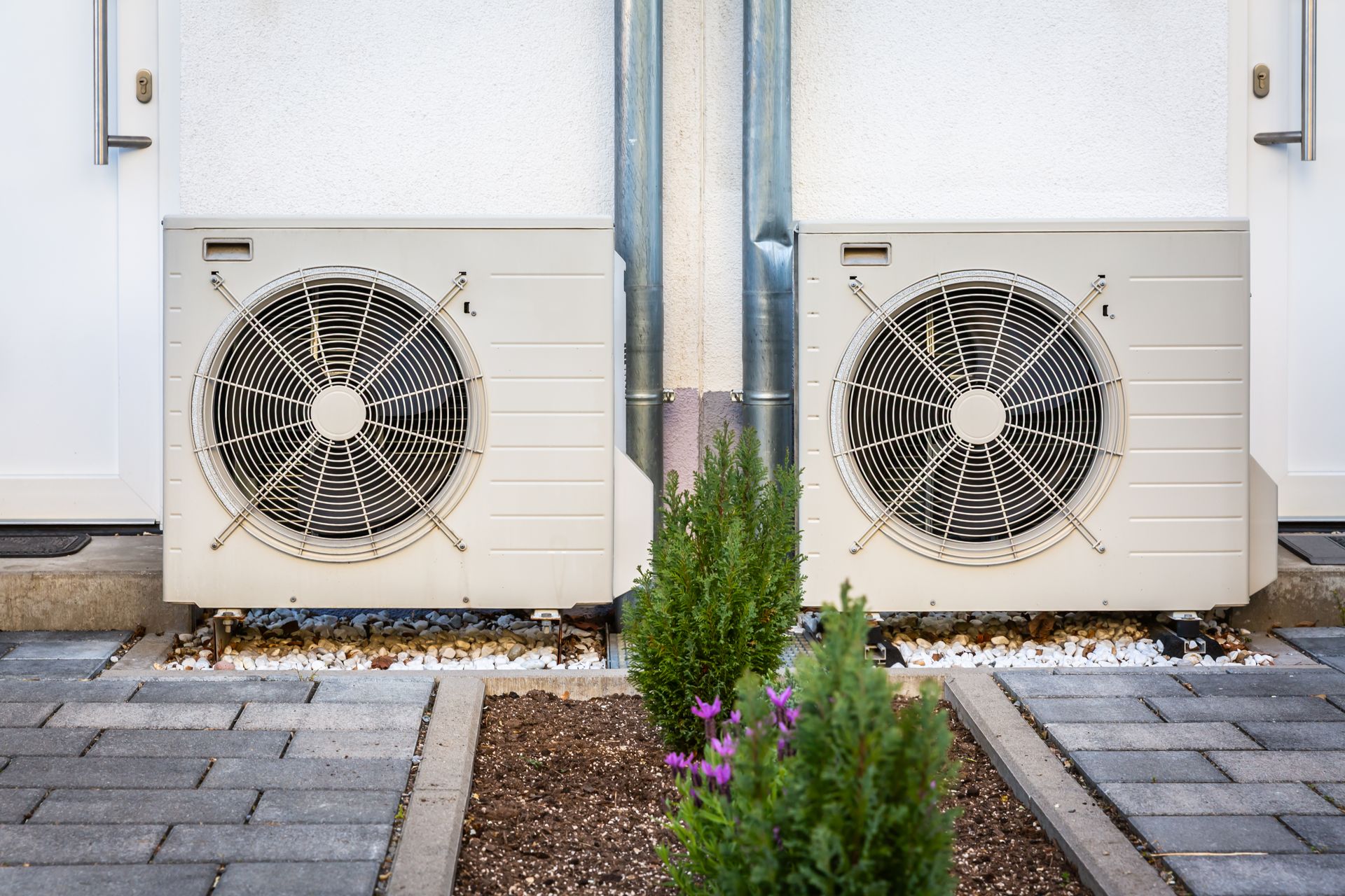 Two air compressors of air conditioning units outside a building.