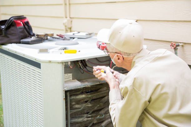 An experienced HVAC maintenance contractor inspecting an outdoor AC unit.