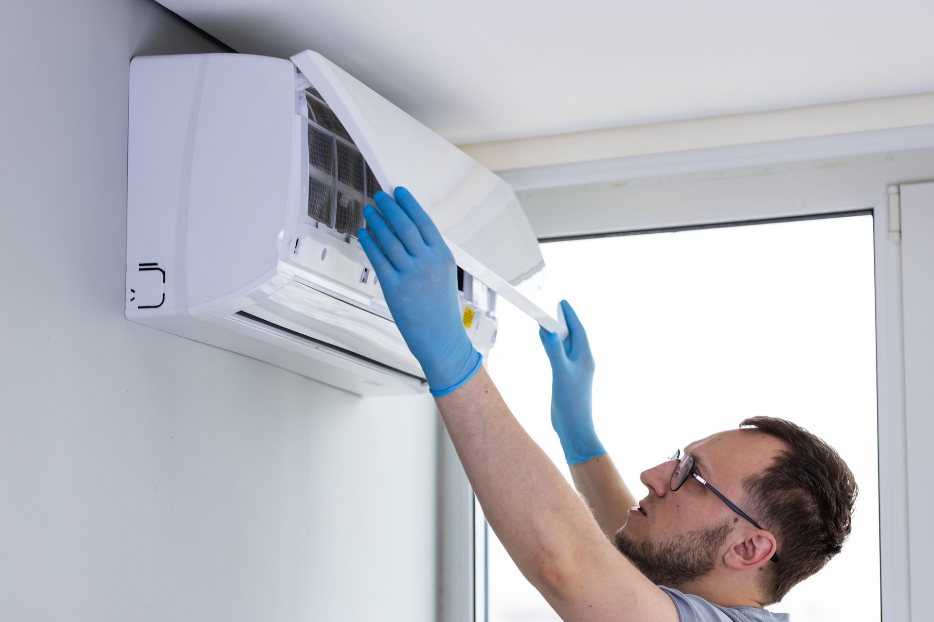 Residential air conditioning contractor lifting AC cover for maintenance at modern apartment. Residential air conditioning contractor lifting AC cover for maintenance at modern apartment.