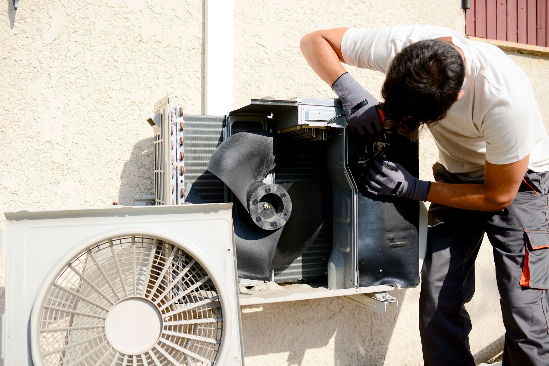 Technician repairing outdoor air conditioning unit for HVAC maintenance.