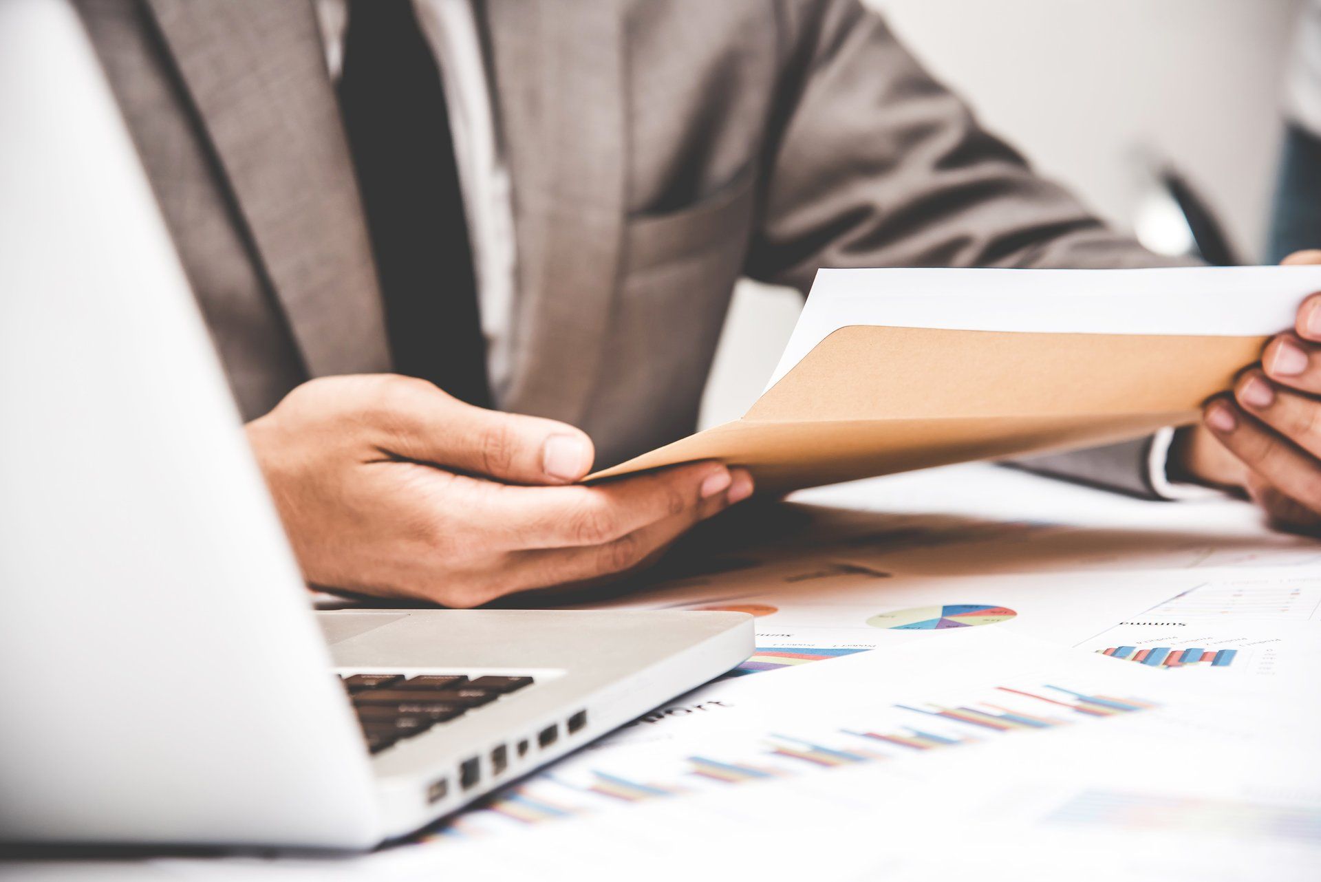 A man in a suit and tie is sitting at a desk holding a piece of paper.