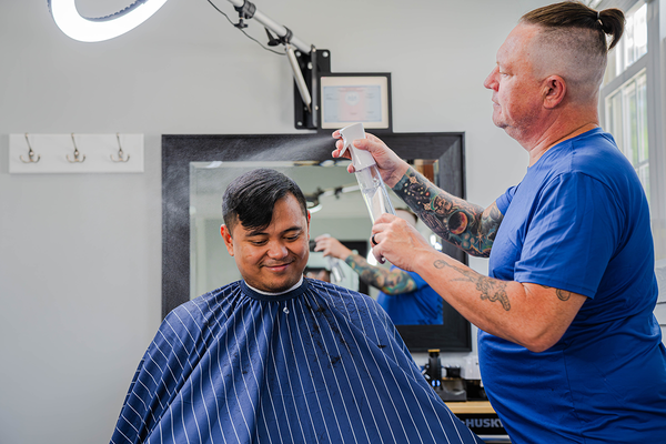 A man is getting his hair cut by a barber in a barber shop.