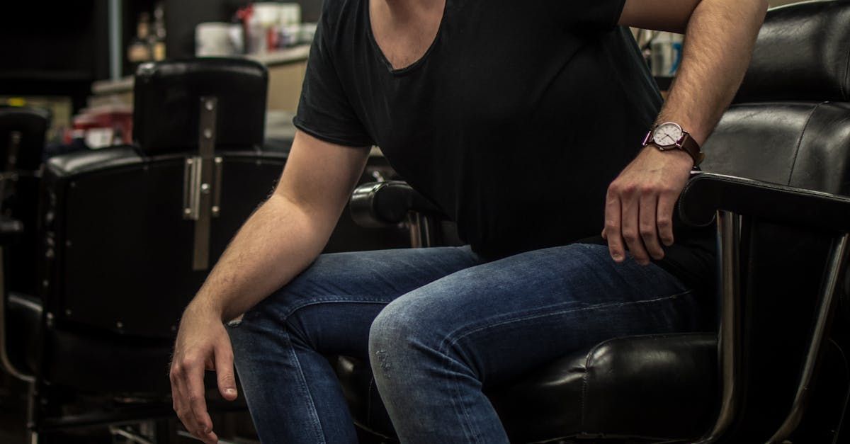A man is sitting in a barber chair in a barber shop.