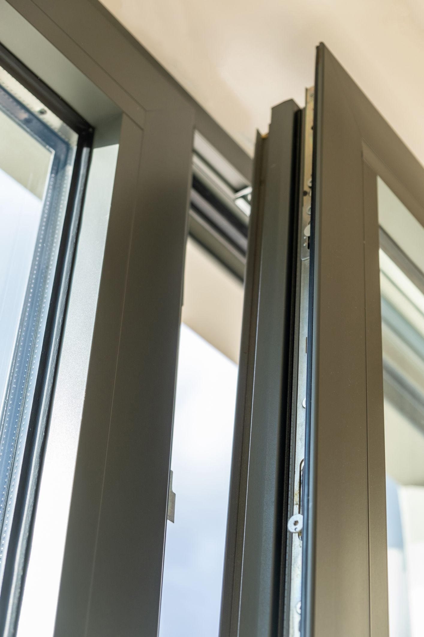 Primo piano del telaio di una finestra grigio scuro leggermente aperto, che rivela il meccanismo interno.