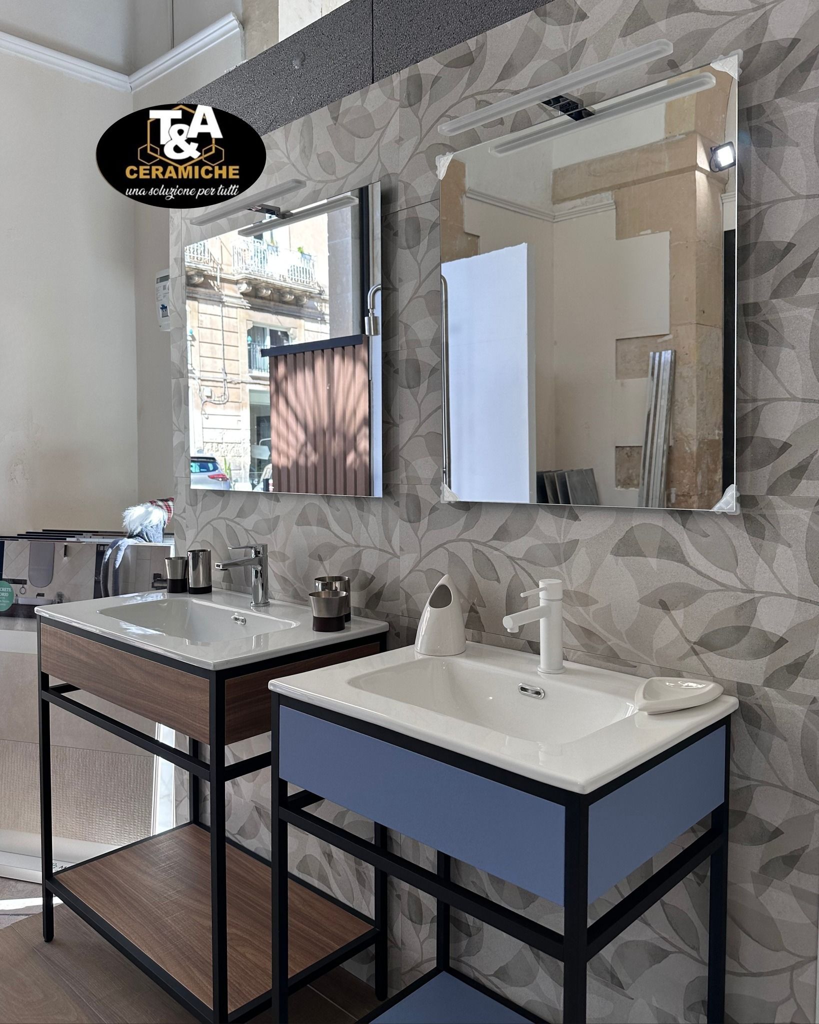 Espositore da bagno con due lavandini, specchi e carta da parati con motivo a foglie.