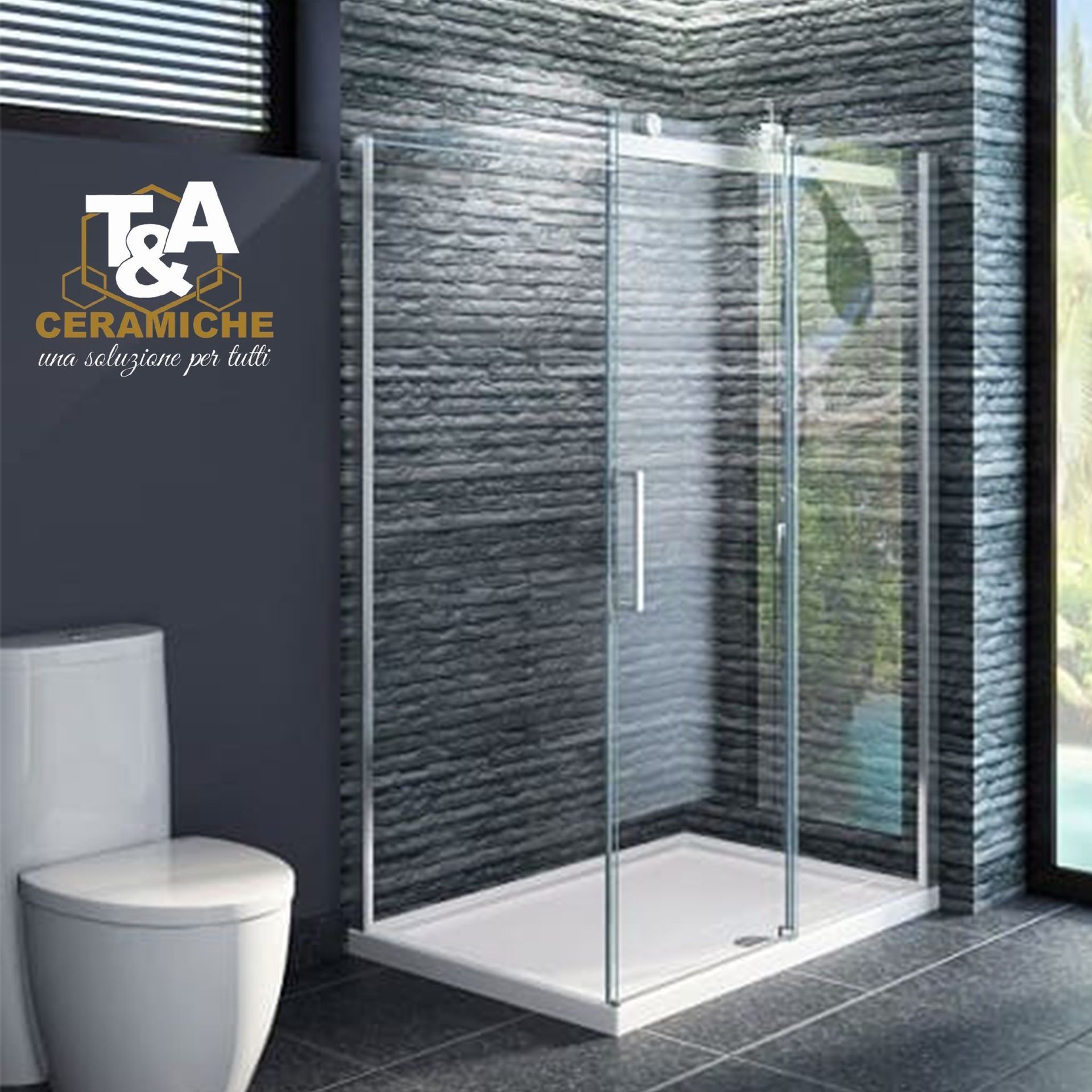 Box doccia con porte in vetro trasparente e base bianca in un bagno con parete in pietra grigio scuro.