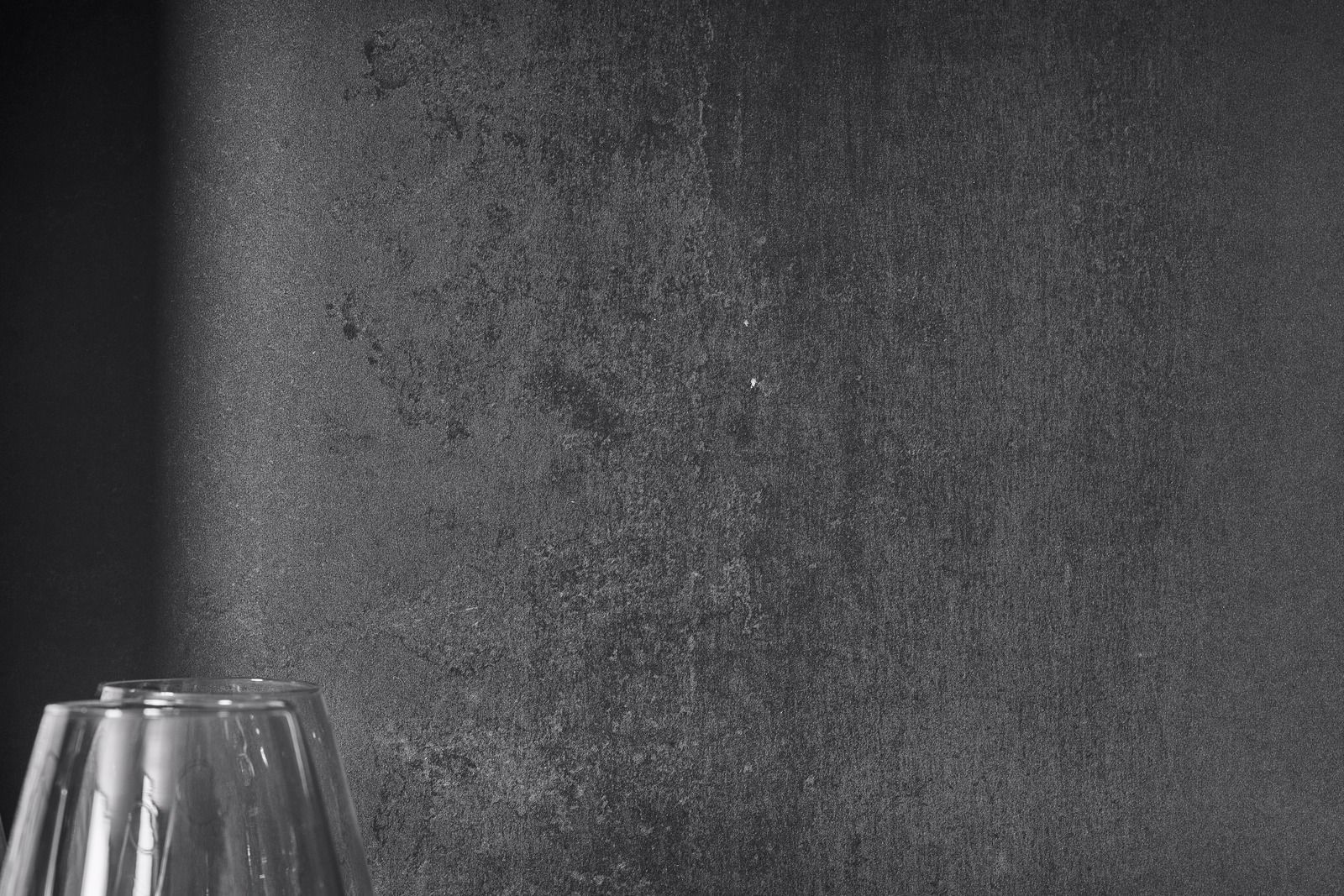 Due oggetti di vetro davanti a una parete scura e ruvida.