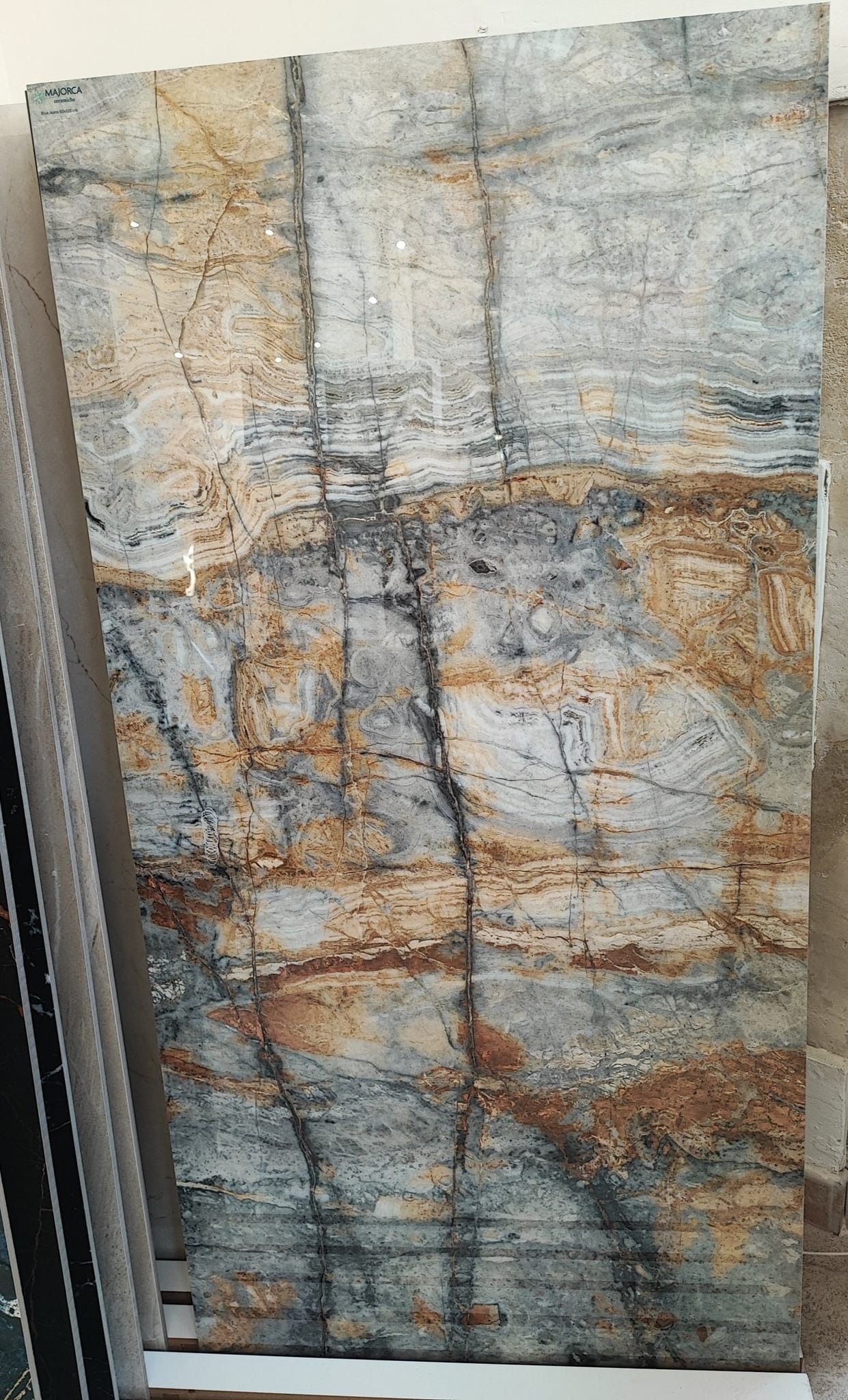 Grande piastrella rettangolare con un disegno astratto a strati nei toni tenui del blu, del beige e del marrone.