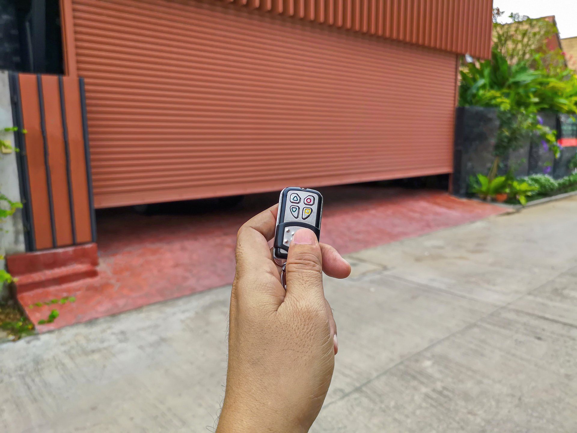 a person is holding a remote control in front of a garage door .