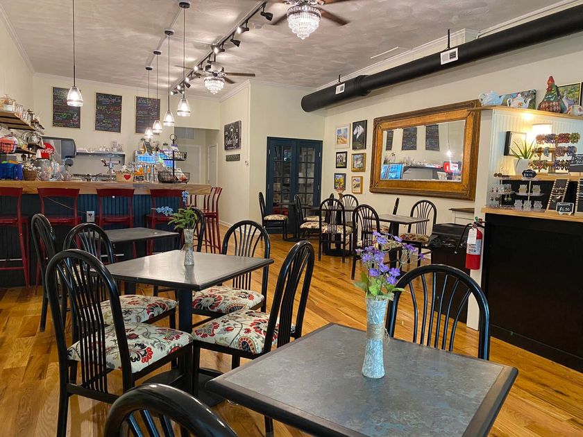 A restaurant with tables and chairs and a vase of flowers on the table.