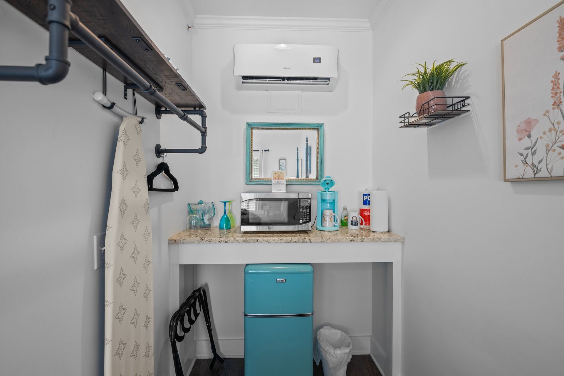 A small kitchen with a refrigerator , microwave , and ironing board.