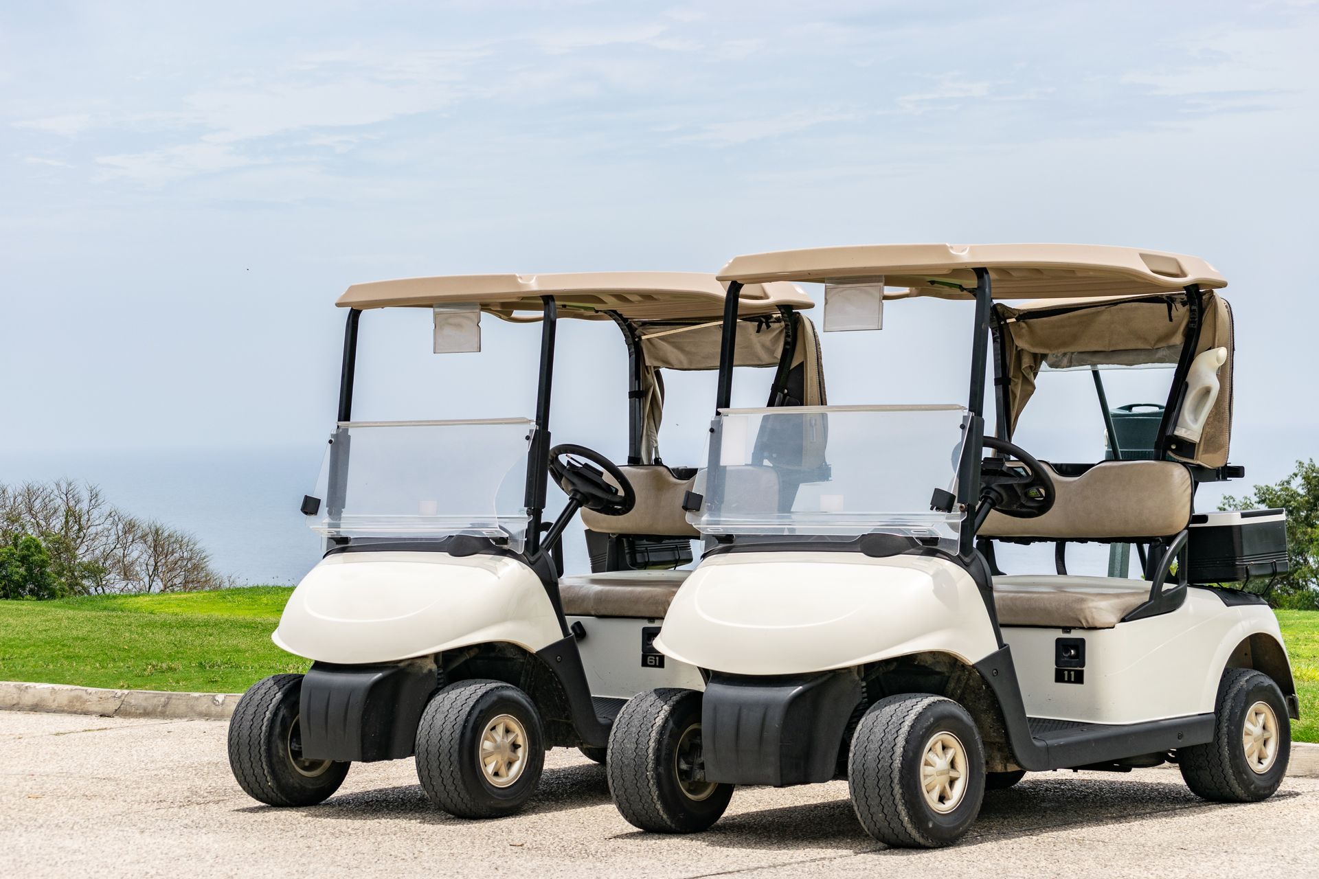 Two golf carts are parked next to each other on a golf course.