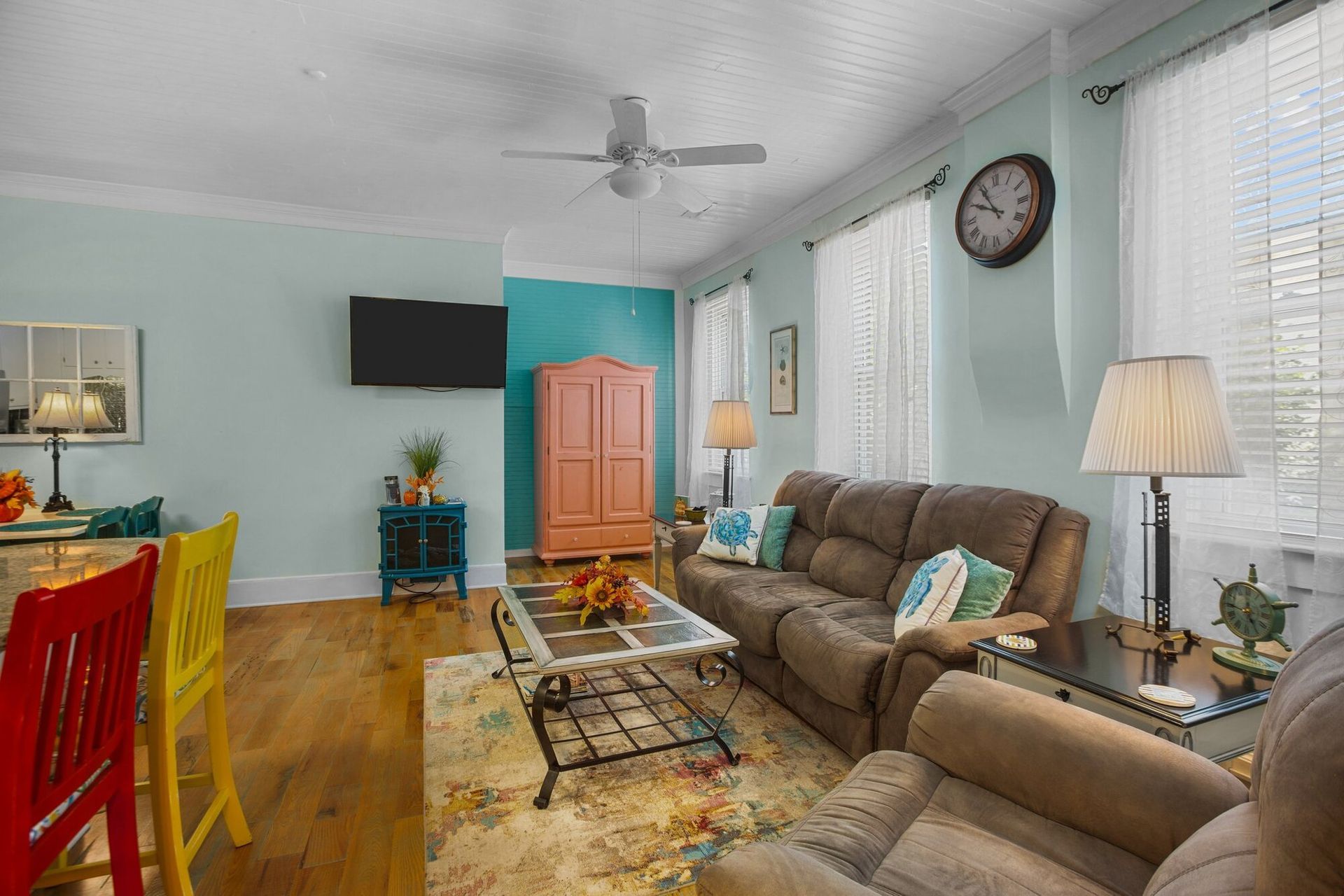 A living room with a couch , chairs , table and television.