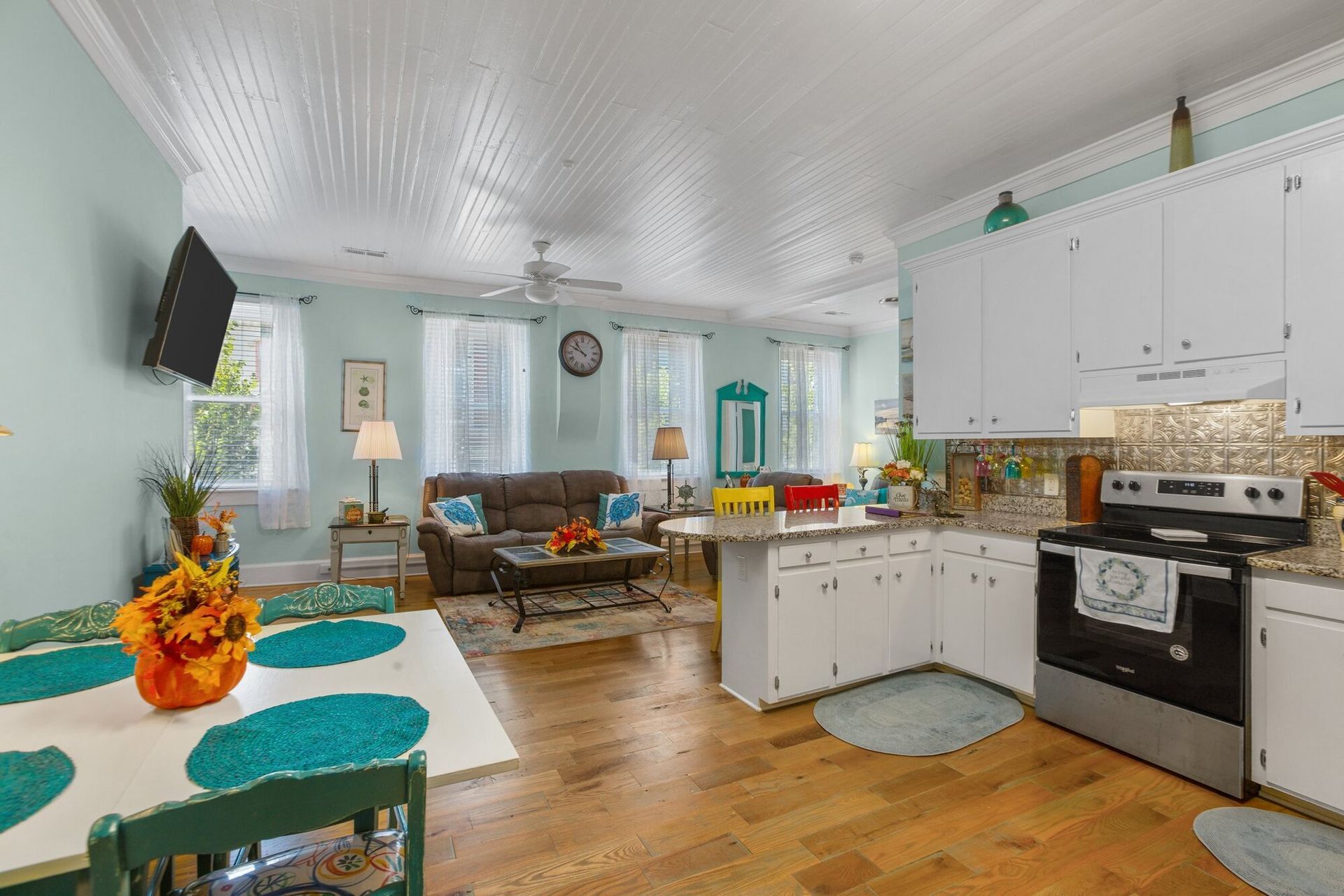 A kitchen with white cabinets , a stove , a table and chairs.