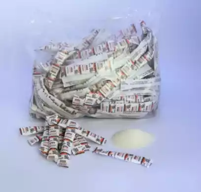 Bolsa de plástico transparente rebosante de pequeños paquetes enrollados blancos y rojos sobre un fondo azul claro.