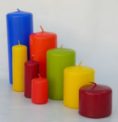 Velas cilíndricas de colores azul, amarillo, rojo, verde y granate sobre un fondo claro.