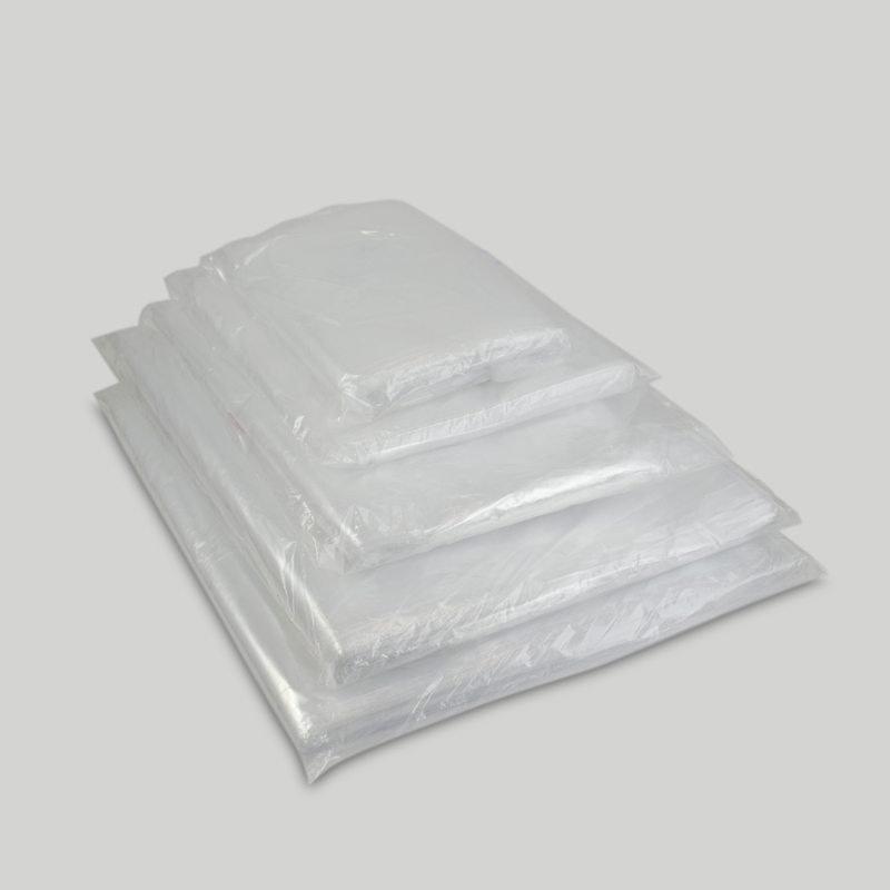 Pila de almohadas o cojines doblados y envueltos en plástico transparente sobre un fondo gris claro.