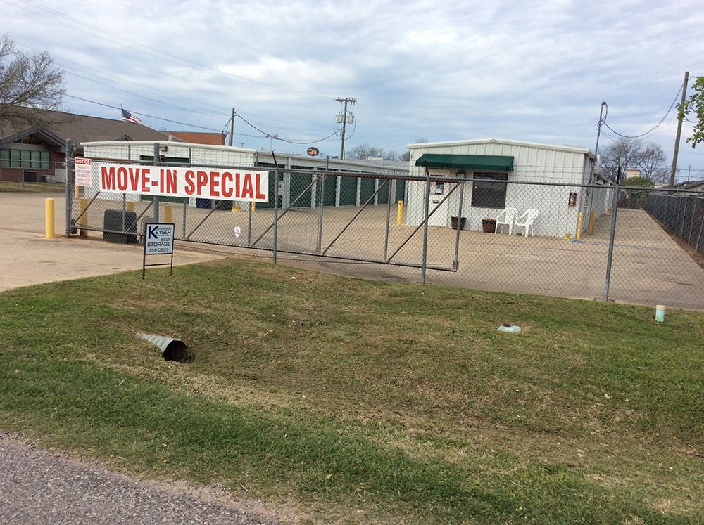 A row of green garage doors on a brick building.