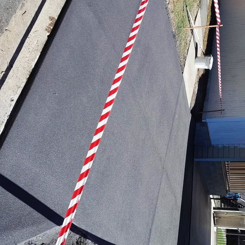 A Red and White Striped Tape is on the Side of a Road — Troys Concrete Overlays in Hillcrest, QLD