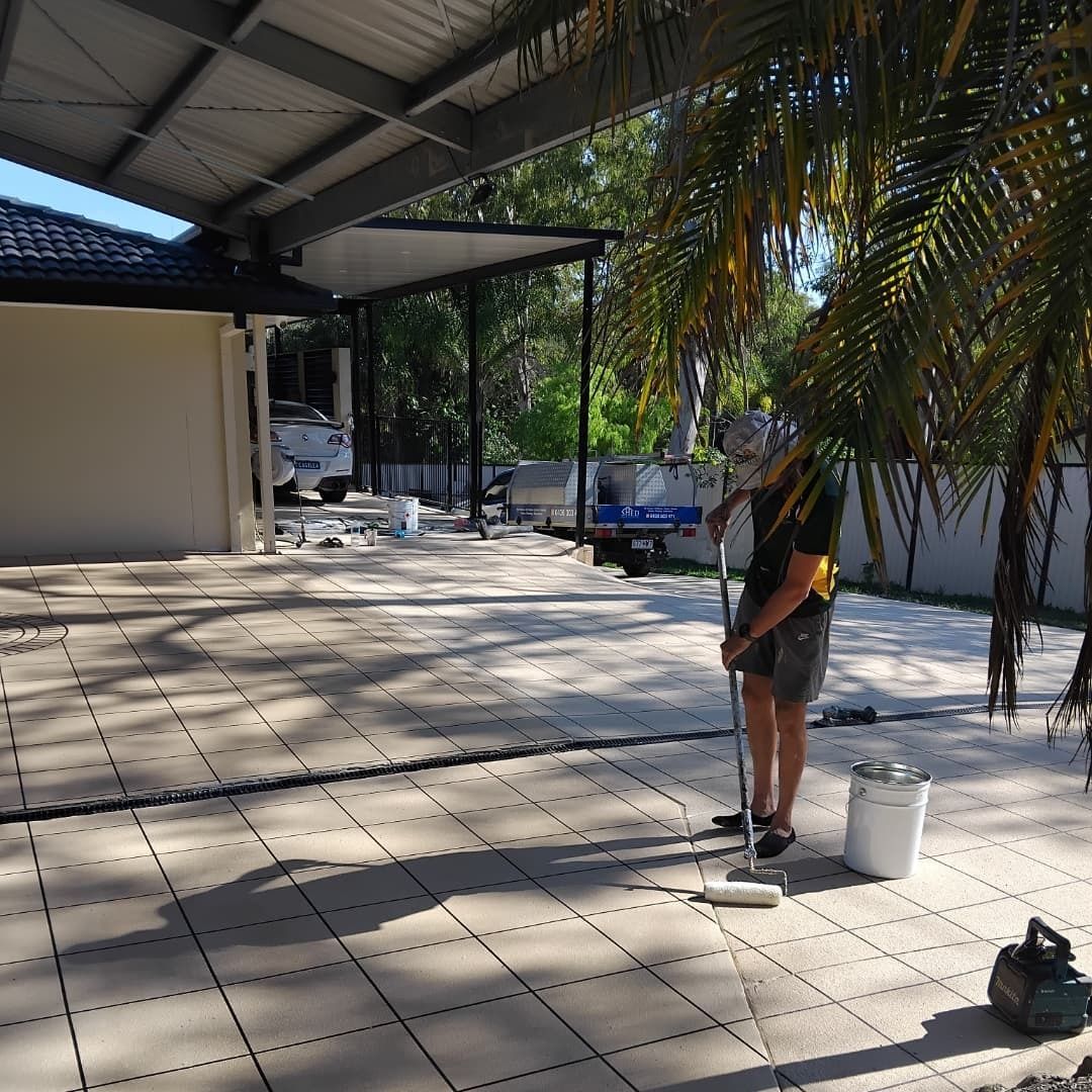 Person Painting a Patio, Standing With Roller and Bucket — Troys Concrete Overlays in Hillcrest, QLD