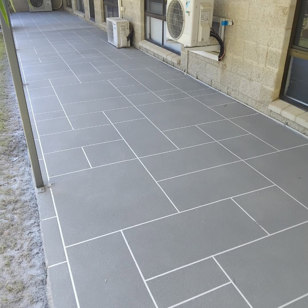 Gray patio pavers with white lines, outside a building with air conditioning units.