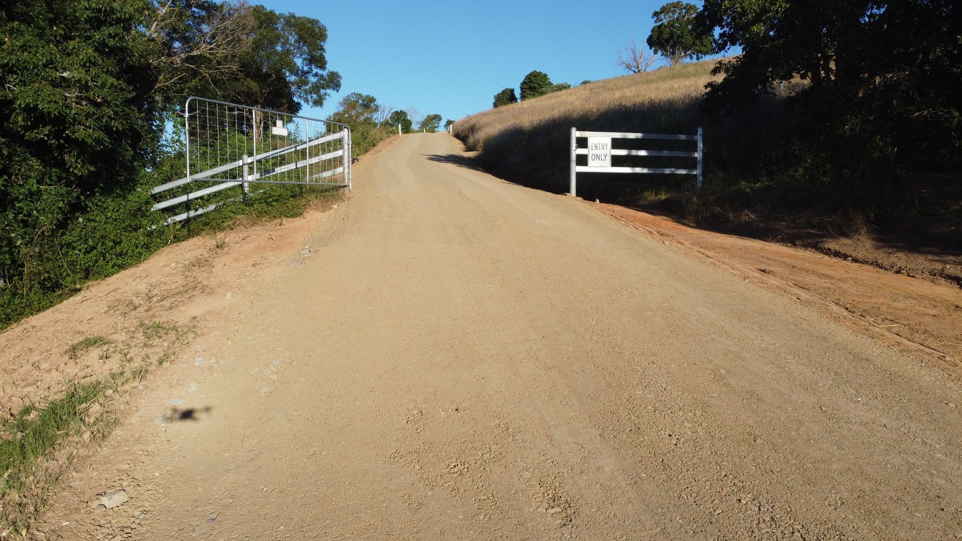 A Dirt Road Ascends a Hill, Flanked by White Fences and Trees — S M & A J Gilbert Earthmoving in Mitchells Island, NSW