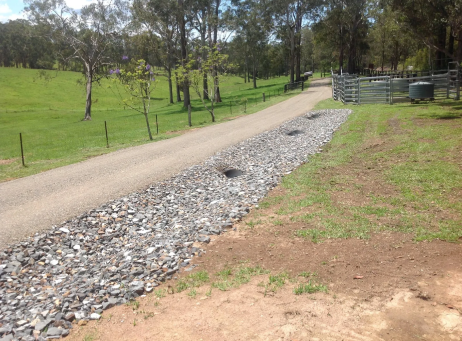 Gravel Driveway With Stone Drainage System Alongside It, Next to Green Grass — S M & A J Gilbert Earthmoving in Mitchells Island, NSW