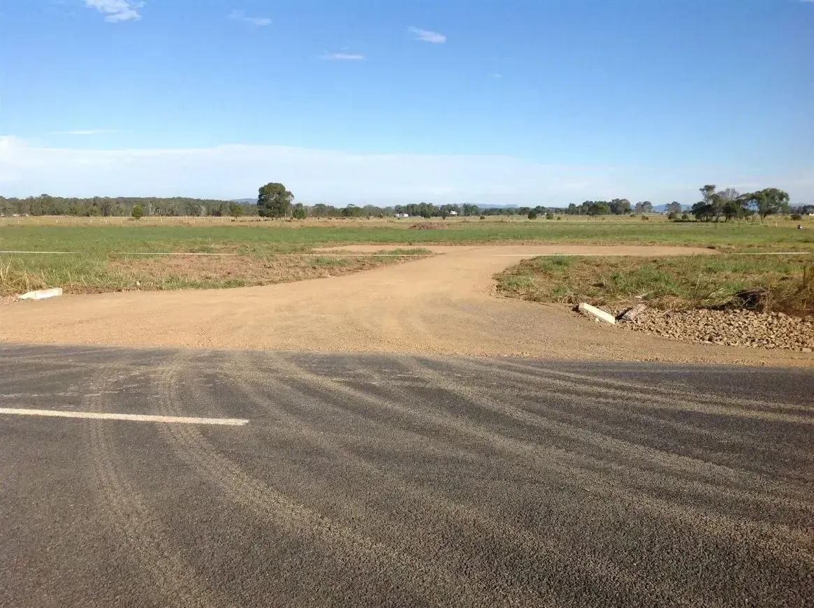 A Dirt Road Going Through a Field With a Blue Sky in the Horizon — S M & A J Gilbert Earthmoving in Mitchells Island, NSW