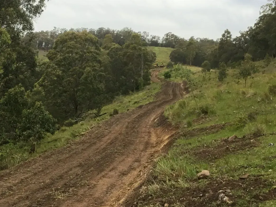 A Rough Road Going Through a Grassy Field With Trees on the Side — S M & A J Gilbert Earthmoving in Mitchells Island, NSW