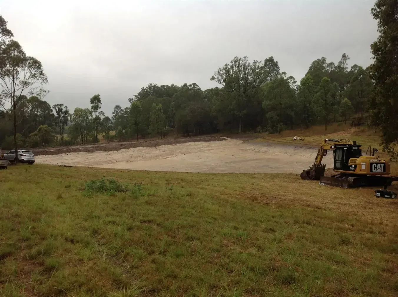 An Orange Cat Excavator is Working in a the Right Side of the Photo — S M & A J Gilbert Earthmoving in Mitchells Island, NSW
