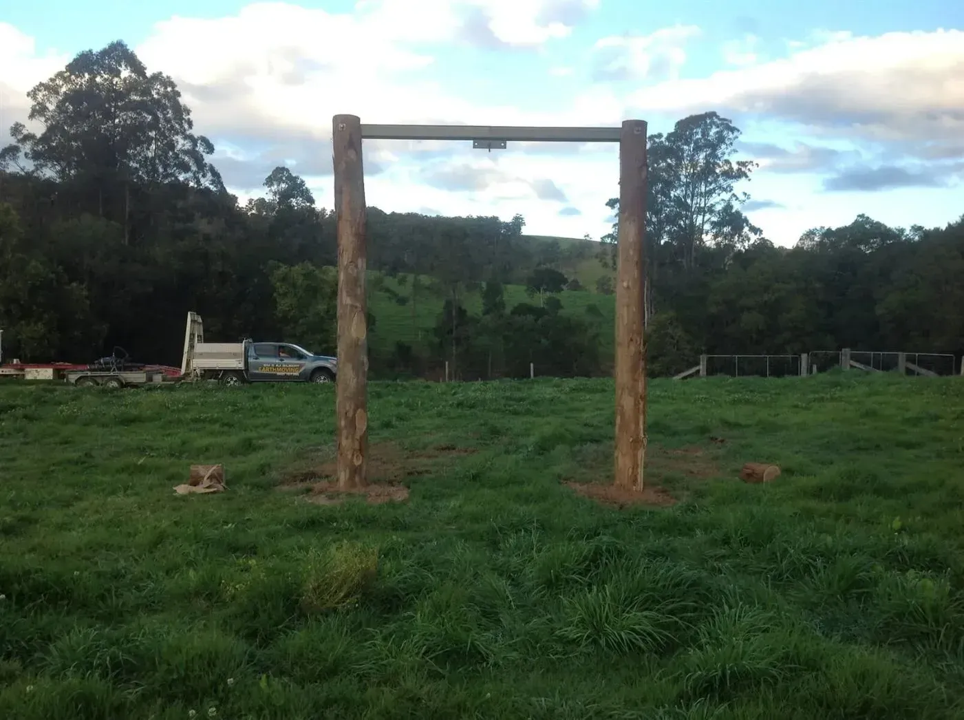 Two Large Wooden Poles in the Middle of a Grassy Field — S M & A J Gilbert Earthmoving in Mitchells Island, NSW
