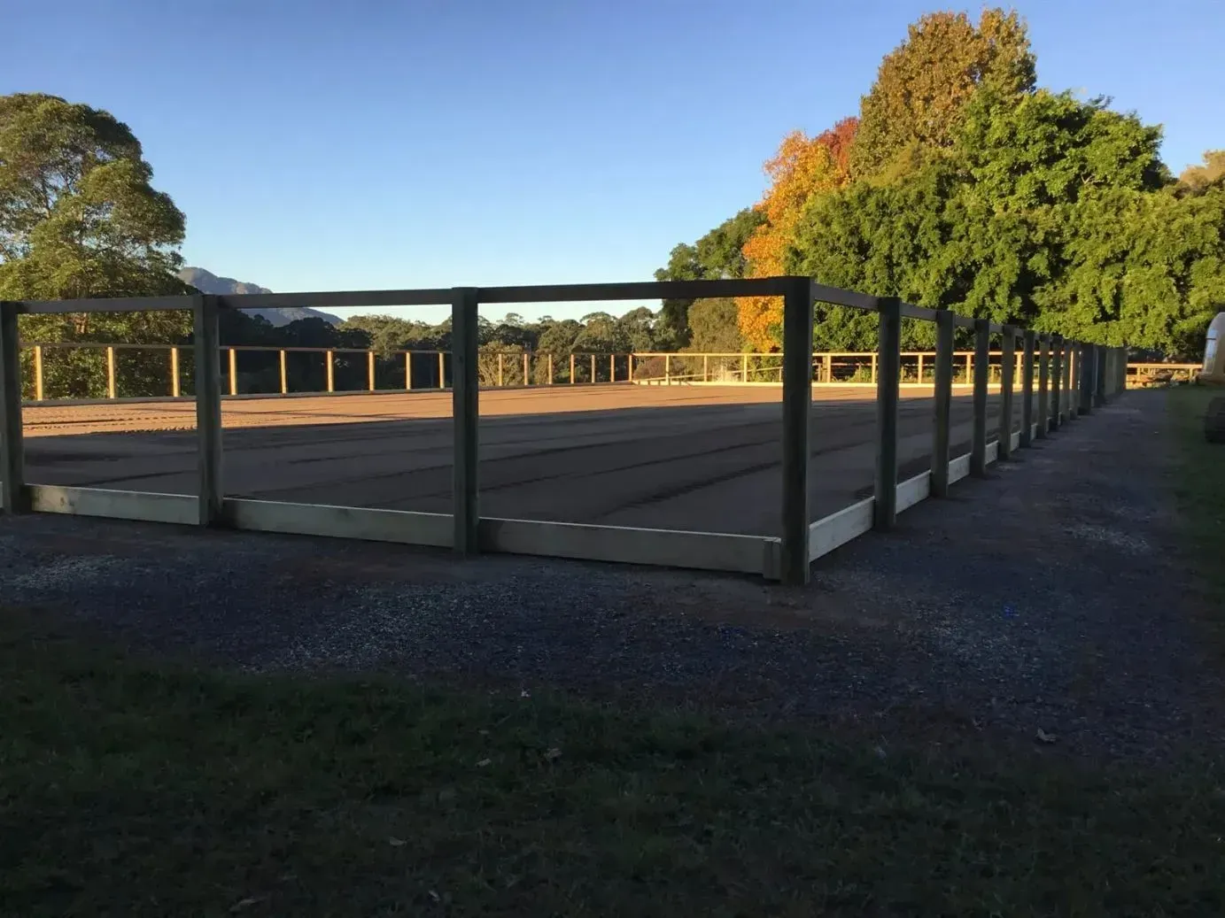 A Wooden Fence Surrounds an Sowing Field With Trees in the Background — S M & A J Gilbert Earthmoving in Mitchells Island, NSW