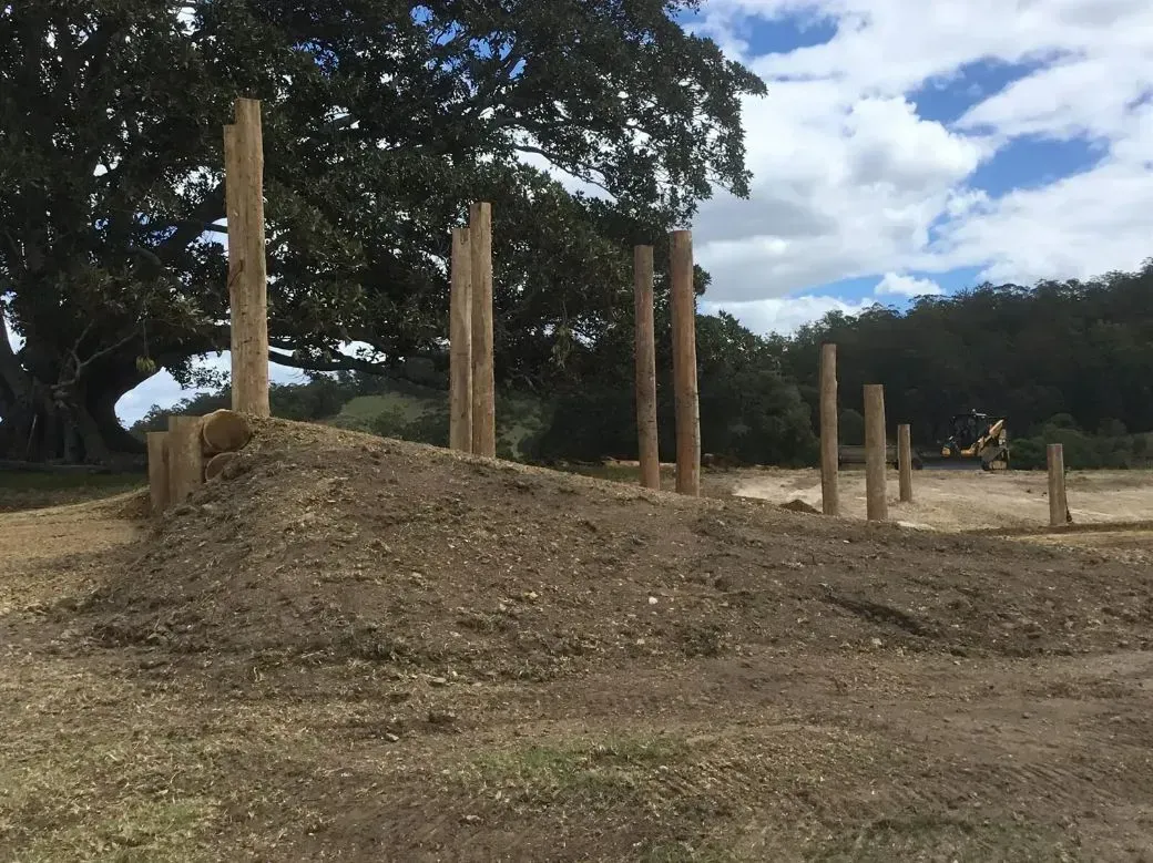 A Pile of Wooden Poles Sitting on Top of a Hill in a Field — S M & A J Gilbert Earthmoving in Mitchells Island, NSW