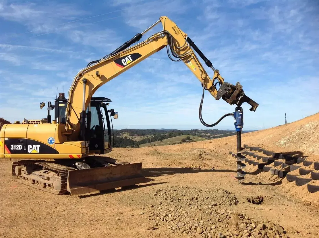 A Right Side View Of A Yellow Cat Excavator is Sitting on Top of a Dirt Hill — S M & A J Gilbert Earthmoving in Mitchells Island, NSW