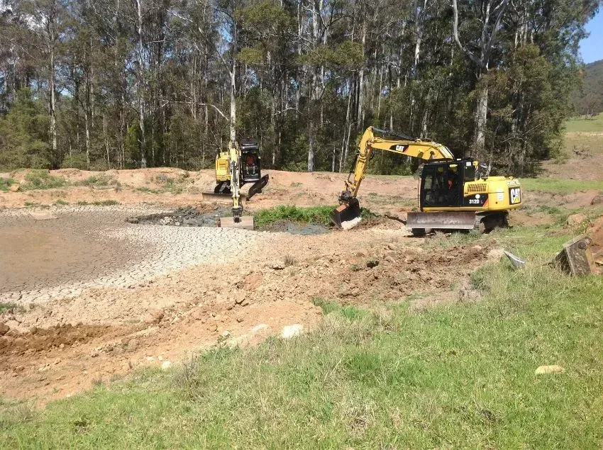 A Couple of Construction Vehicles Are Working in a Field — S M & A J Gilbert Earthmoving in Mitchells Island, NSW