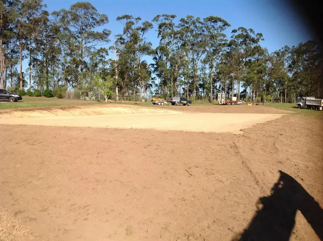 A Shadow of a Person is Cast on a White Sand Field With Trees — S M & A J Gilbert Earthmoving in Mitchells Island, NSW