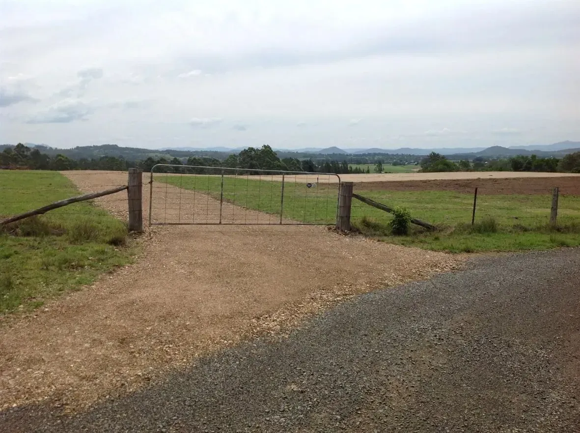 A Gravel Road With a Gate in the Middle of It Leading to a Field — S M & A J Gilbert Earthmoving in Mitchells Island, NSW