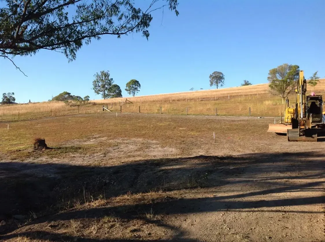 A Yellow Excavator is Parked In The Middle of a Dirt Road — S M & A J Gilbert Earthmoving in Mitchells Island, NSW