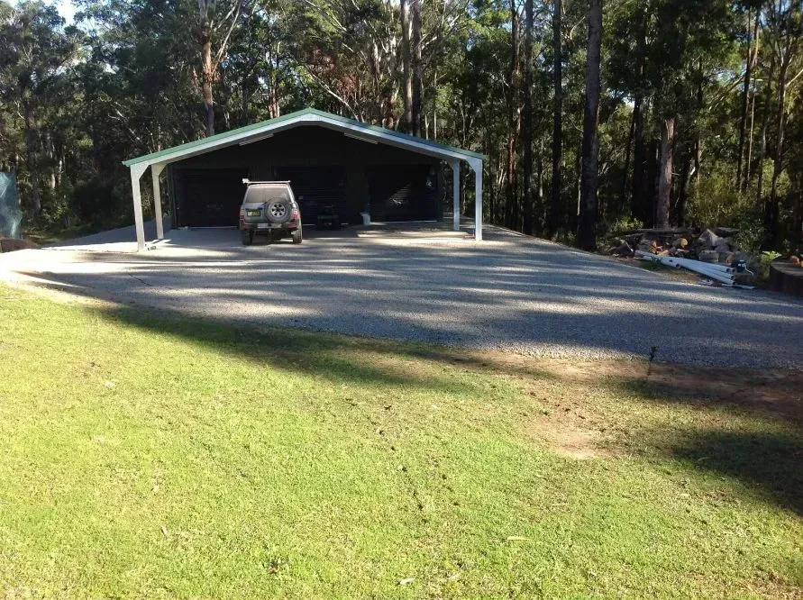 A Car is Parked Under a Shed in the Middle of a Grassy Field — S M & A J Gilbert Earthmoving in Mitchells Island, NSW